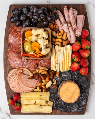 Charcuterie board with a bowl of Torshi mixed pickled vegetables beside salami, cheese and grapes
